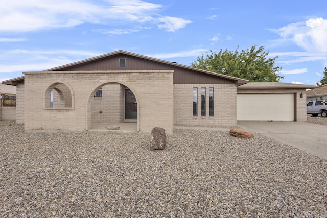 view of front of property featuring brick siding, an attached garage, and driveway