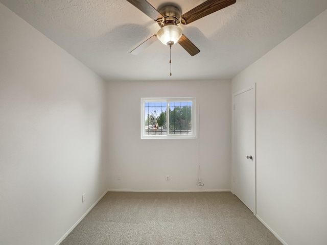 carpeted spare room featuring a textured ceiling and ceiling fan