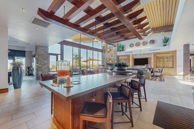 kitchen featuring hanging light fixtures, a kitchen bar, beam ceiling, and high vaulted ceiling