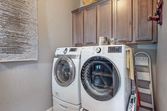 clothes washing area with cabinets and washing machine and clothes dryer