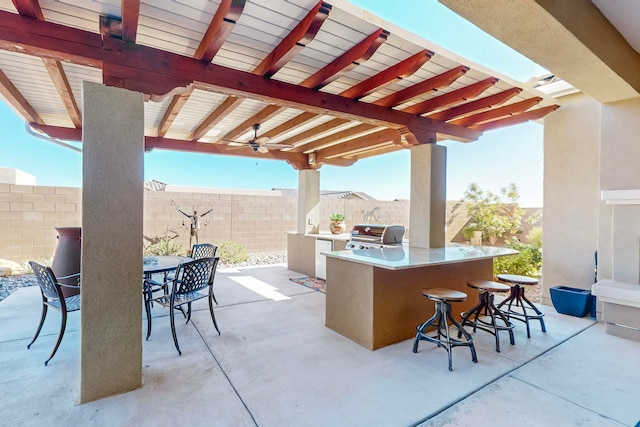 view of patio / terrace with an outdoor bar, a grill, ceiling fan, and exterior kitchen