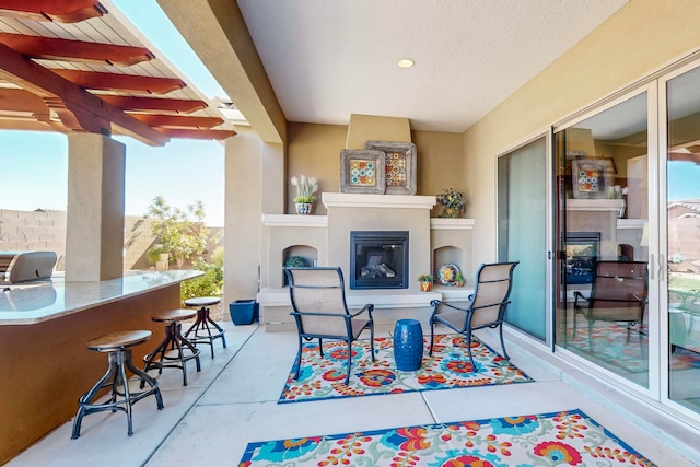 view of patio / terrace featuring an outdoor fireplace and a bar