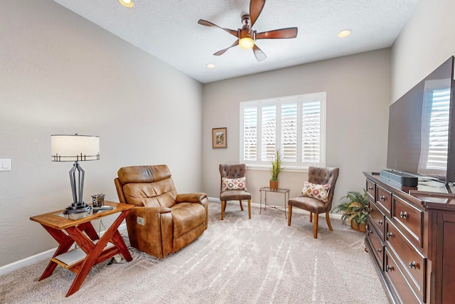 living area with a textured ceiling, light colored carpet, a healthy amount of sunlight, and ceiling fan