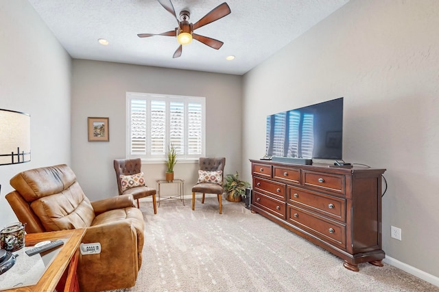 sitting room featuring a textured ceiling, light colored carpet, and ceiling fan