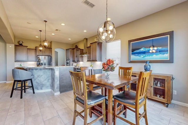 dining area featuring light tile patterned flooring, a chandelier, and sink