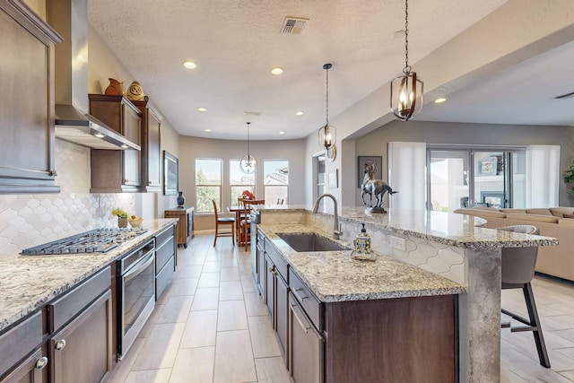 kitchen with a kitchen breakfast bar, a large island with sink, pendant lighting, and sink