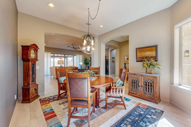 tiled dining area with ceiling fan with notable chandelier