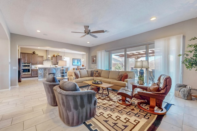 living room with a textured ceiling and ceiling fan