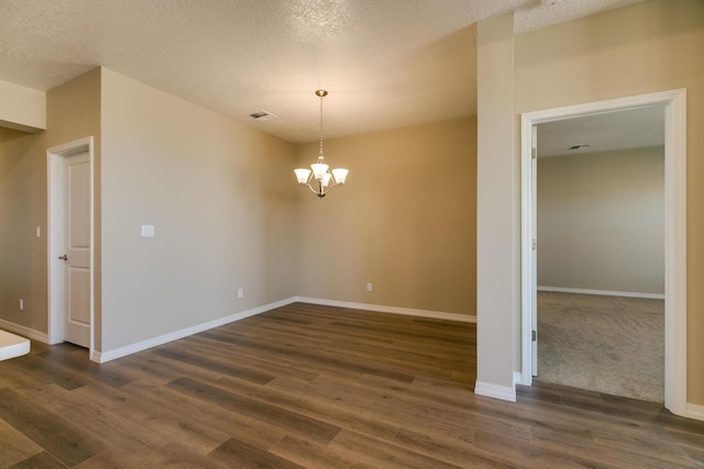 unfurnished room featuring a textured ceiling, a chandelier, and dark hardwood / wood-style flooring