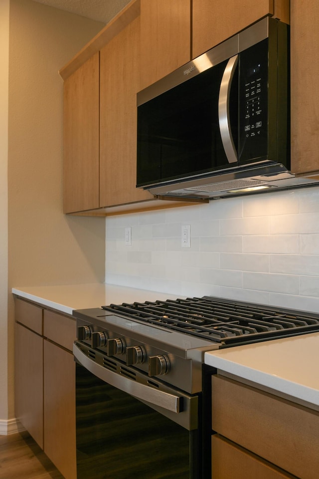 kitchen with hardwood / wood-style flooring, stainless steel appliances, and backsplash