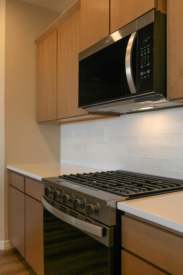 4860 Guadalupe Peak St SW, Los Lunas, NM 87031 - kitchen featuring stainless steel gas range oven, backsplash, light countertops, and wood finished floors