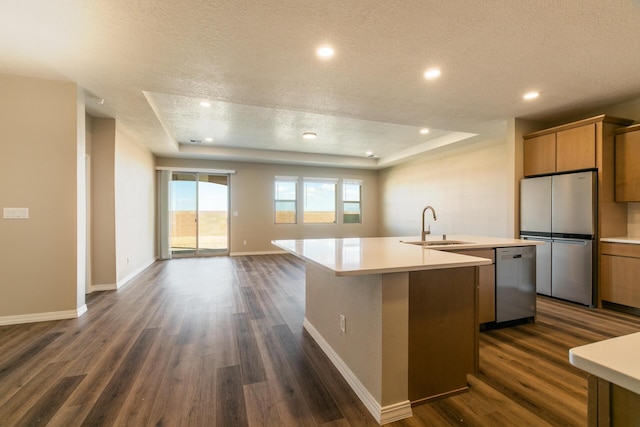 kitchen featuring sink, a textured ceiling, stainless steel appliances, dark wood-type flooring, and an island with sink