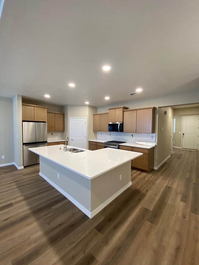 kitchen with sink, appliances with stainless steel finishes, a large island with sink, and dark hardwood / wood-style flooring