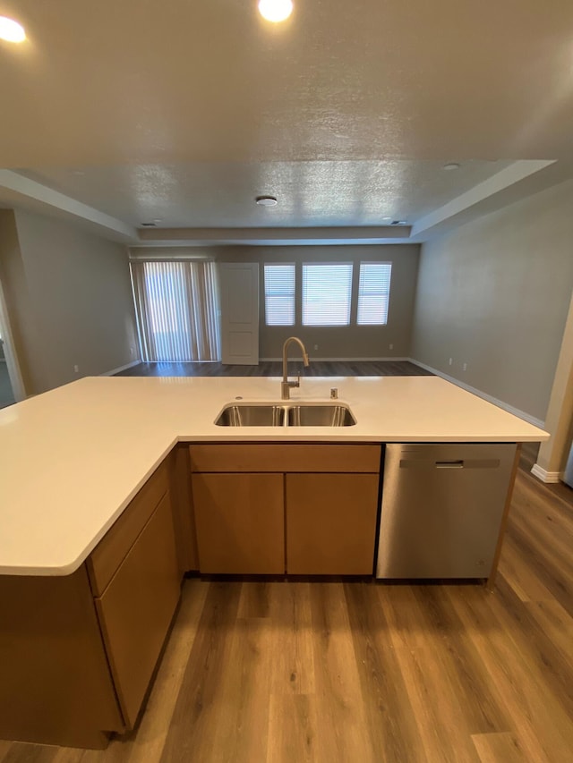 kitchen with a textured ceiling, light hardwood / wood-style flooring, sink, and stainless steel dishwasher