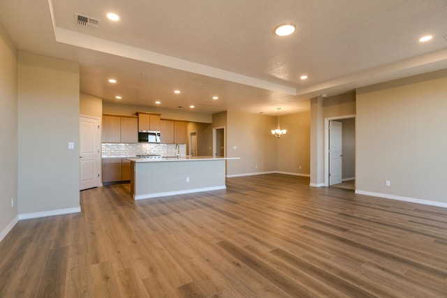 unfurnished living room with sink, dark wood-type flooring, and a chandelier