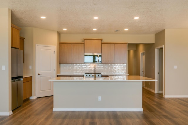 kitchen featuring appliances with stainless steel finishes, backsplash, a textured ceiling, dark hardwood / wood-style floors, and an island with sink