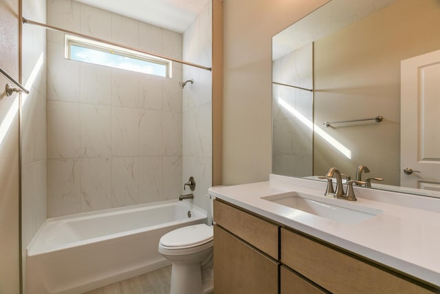 full bathroom featuring vanity, tiled shower / bath, and toilet