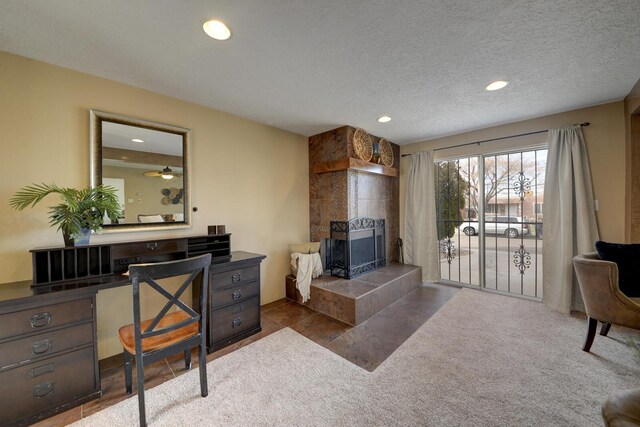 tiled living room featuring a tile fireplace, ceiling fan, and a textured ceiling