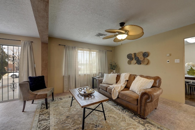 living room featuring beam ceiling, ceiling fan, plenty of natural light, and light colored carpet