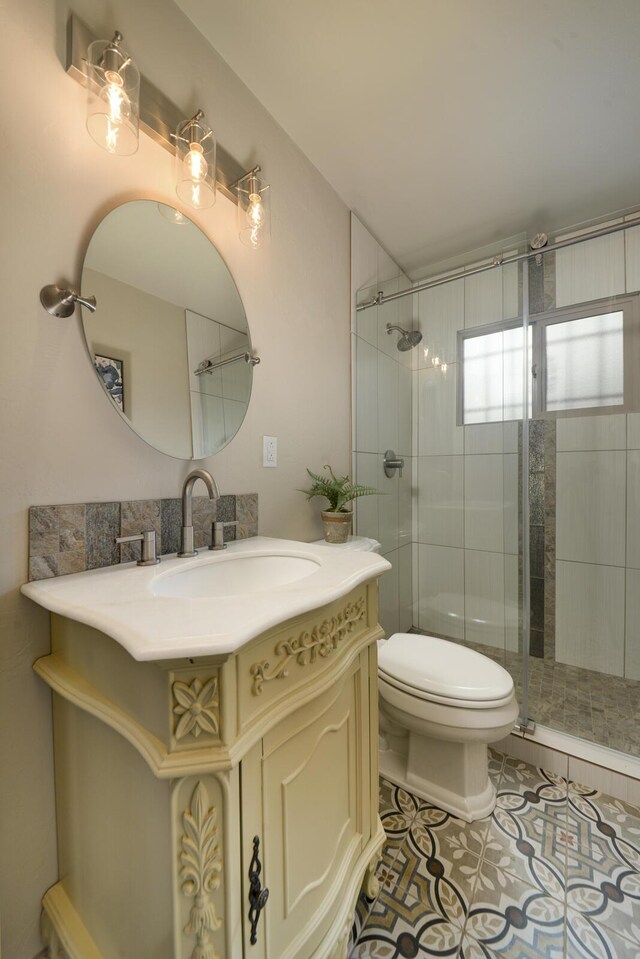 bathroom featuring tile patterned flooring, vanity, a shower with shower door, and toilet