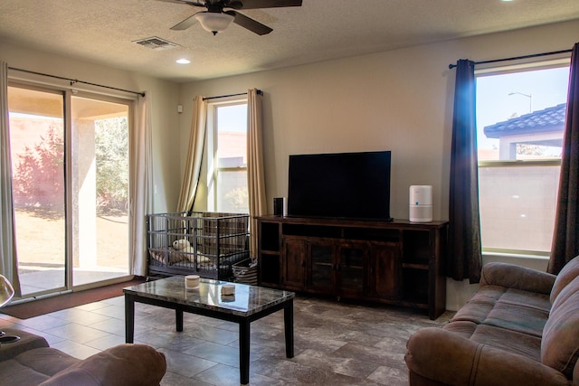 living room with ceiling fan, a healthy amount of sunlight, and a textured ceiling