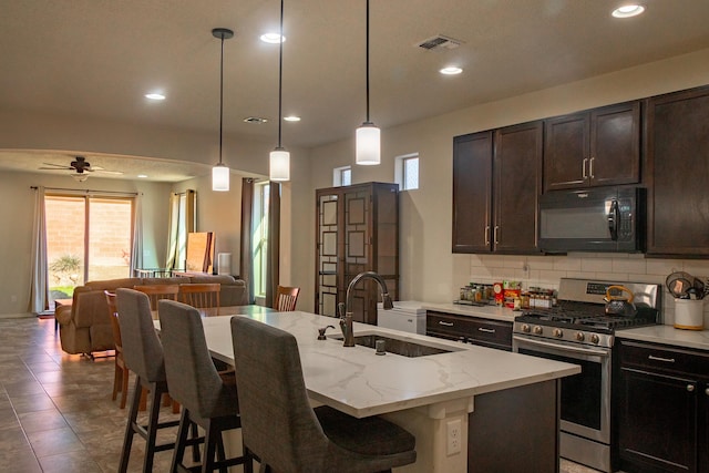 kitchen featuring pendant lighting, sink, an island with sink, stainless steel range, and ceiling fan