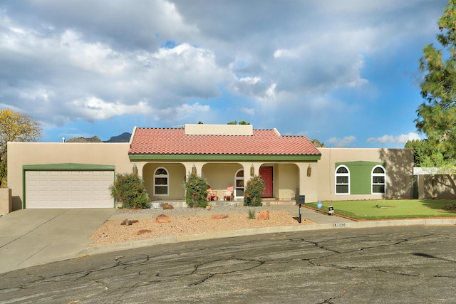 view of front of property with stucco siding, covered porch, concrete driveway, a garage, and a tiled roof