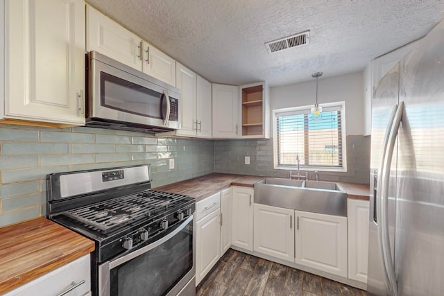 kitchen featuring butcher block counters, white cabinets, decorative light fixtures, and stainless steel appliances