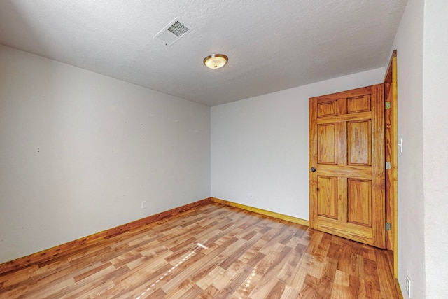 empty room featuring light wood-type flooring and a textured ceiling