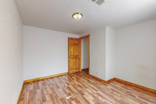 unfurnished room with light hardwood / wood-style flooring and a textured ceiling