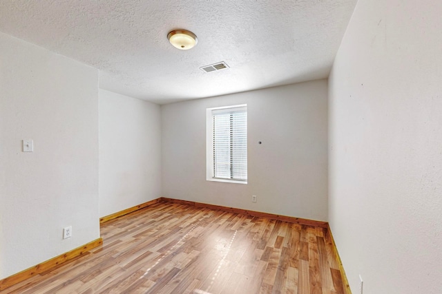 unfurnished room featuring a textured ceiling and light hardwood / wood-style floors