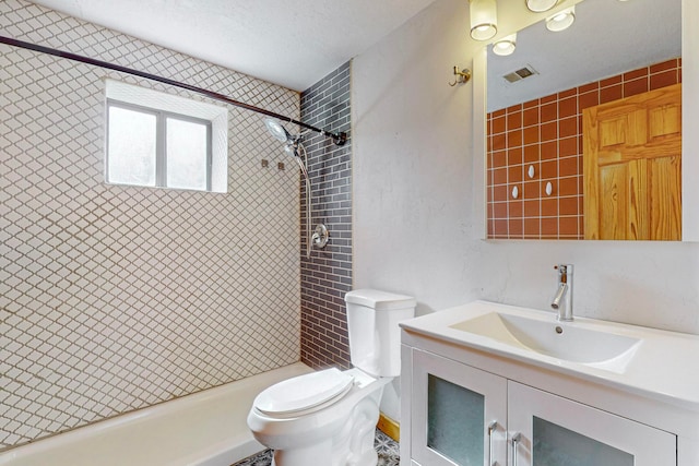 bathroom featuring tiled shower, vanity, a textured ceiling, and toilet