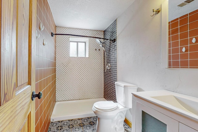 bathroom with vanity, a textured ceiling, toilet, and tiled shower