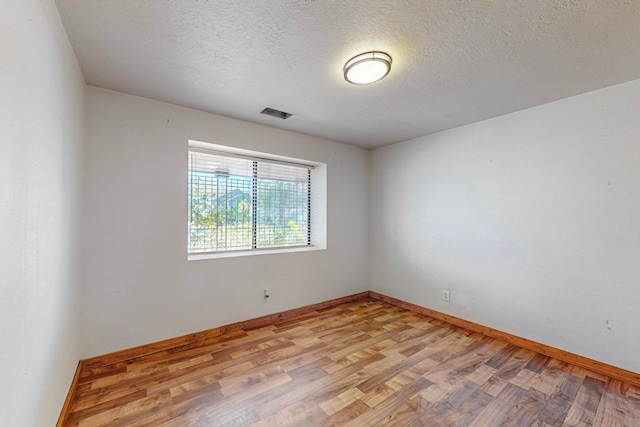 spare room with a textured ceiling and light wood-type flooring