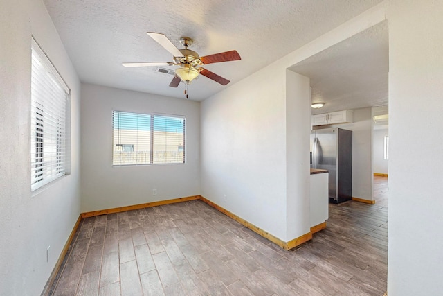 unfurnished room featuring ceiling fan, wood-type flooring, and a textured ceiling