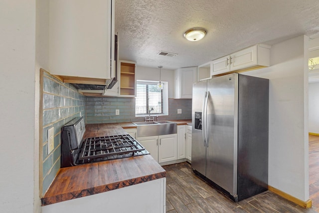 kitchen featuring sink, stainless steel fridge with ice dispenser, wood counters, white cabinetry, and black stove