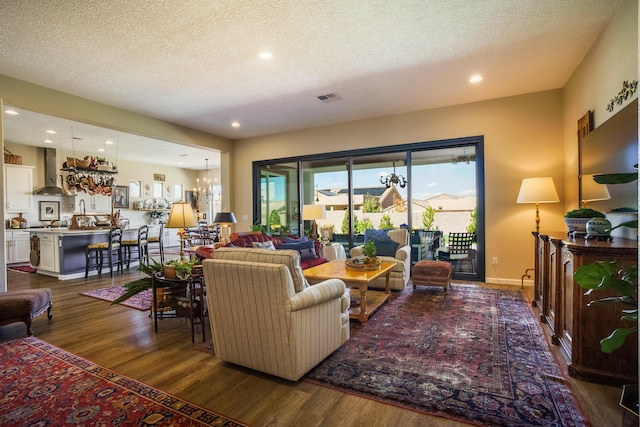 living room with dark wood-type flooring, a textured ceiling, and a notable chandelier