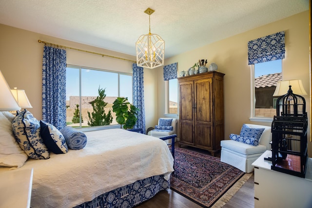 bedroom with an inviting chandelier, dark hardwood / wood-style floors, a textured ceiling, and multiple windows