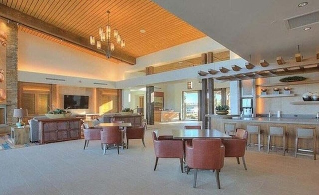 dining space featuring a high ceiling, beamed ceiling, a notable chandelier, and wood ceiling