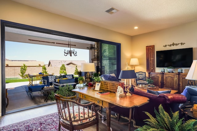 living room featuring hardwood / wood-style floors, a textured ceiling, a chandelier, and a healthy amount of sunlight