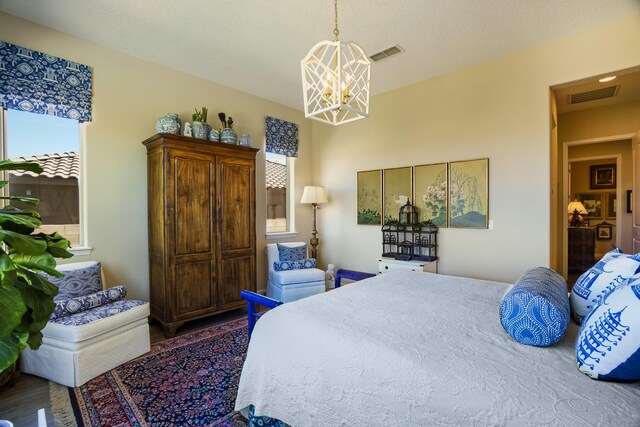 bedroom with dark wood-type flooring, a textured ceiling, and a notable chandelier