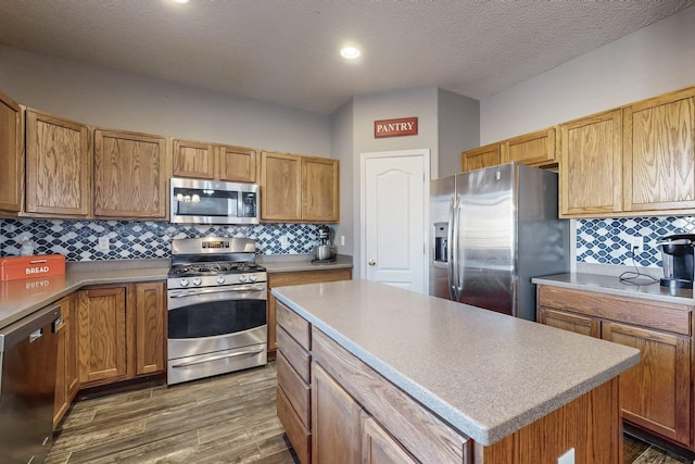 kitchen with a kitchen island, tasteful backsplash, stainless steel appliances, and dark wood-type flooring