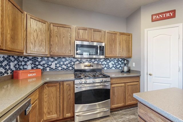 kitchen featuring backsplash, dark hardwood / wood-style flooring, stainless steel appliances, and a textured ceiling