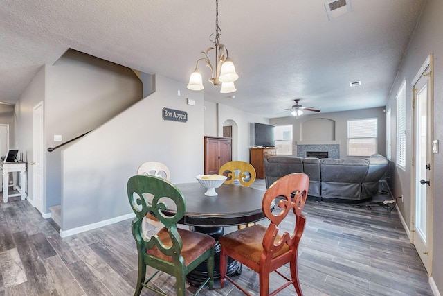 dining room with a textured ceiling, dark hardwood / wood-style flooring, and ceiling fan with notable chandelier