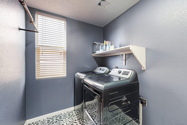 washroom with a textured ceiling and washing machine and dryer