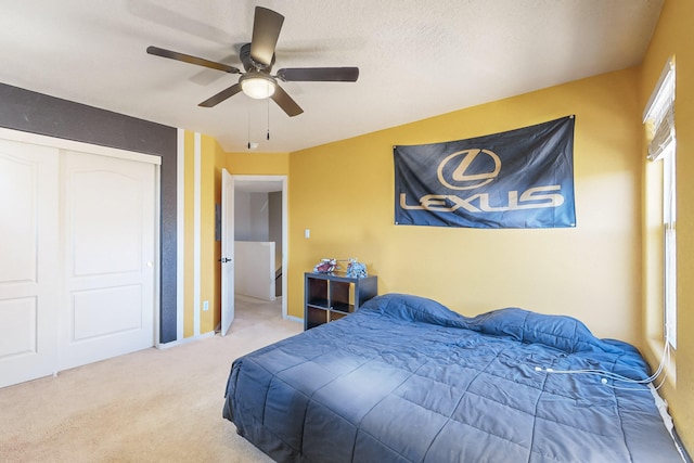 carpeted bedroom featuring ceiling fan, a closet, and a textured ceiling