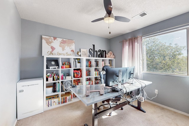 carpeted home office with ceiling fan and a textured ceiling