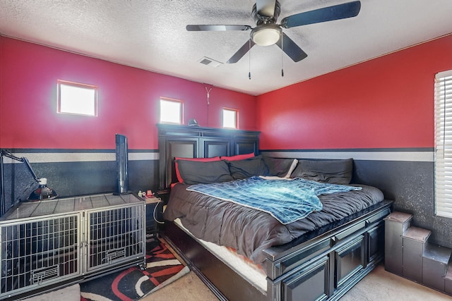 carpeted bedroom featuring ceiling fan and a textured ceiling