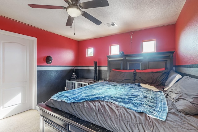 carpeted bedroom featuring ceiling fan and a textured ceiling