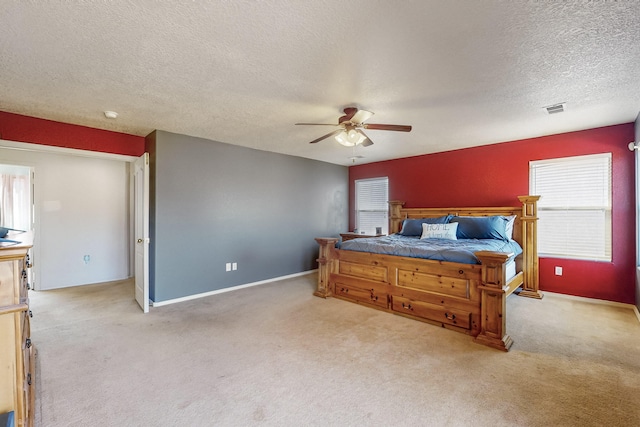 bedroom featuring ceiling fan, light colored carpet, and a textured ceiling